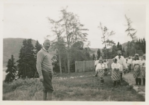 Image of Dr. Hettasch with movie camera, and group of Eskimo [Inuit] children at MacMillan Moravi